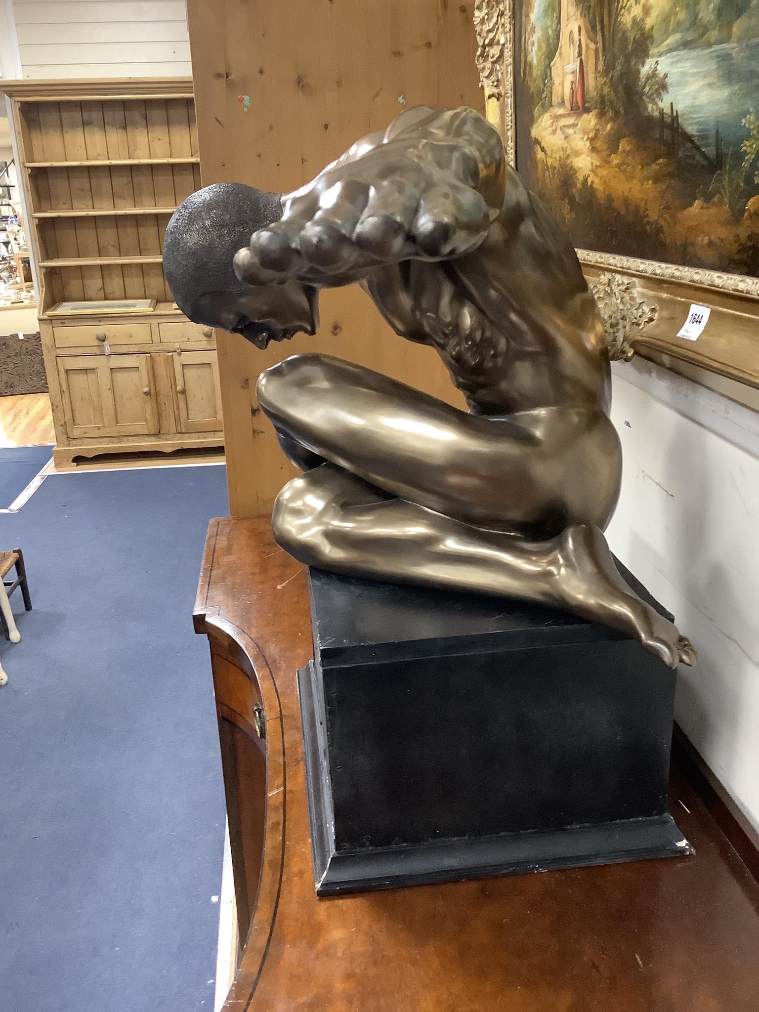 A contemporary bronzed composition figure of a seated male nude, width 138cm, height 68cm